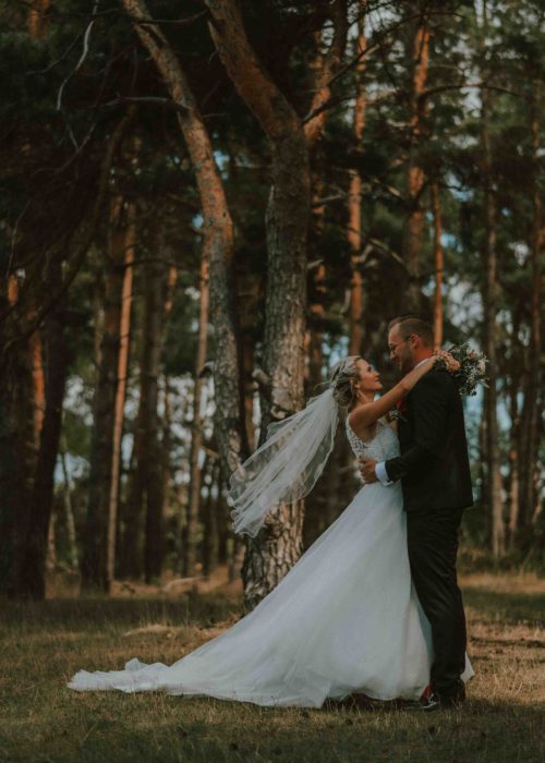 Hochzeit (1404) Brautpaar mit Hochzeitsfotos fotografiert von professioneller Fotografin oder Hochzeitsfotografin in einem Wald in Hochzeitskleid und Anzug mit langem Schleier.